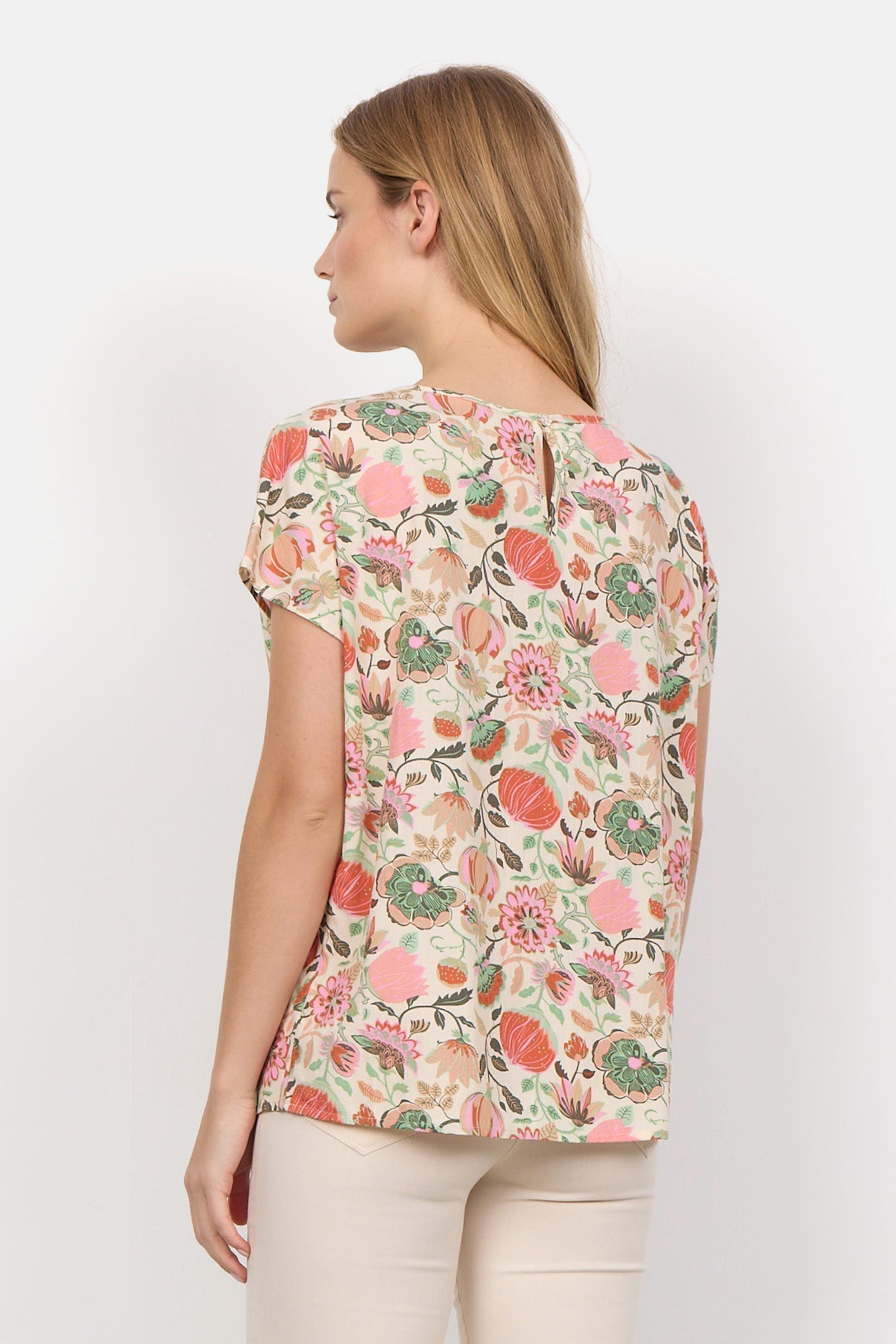 Back view of Soya Concept (40579) Women's Short Sleeve Graphic Floral Blouse in a Peach Floral Print With PInk & Green Hues over a Cream Background 