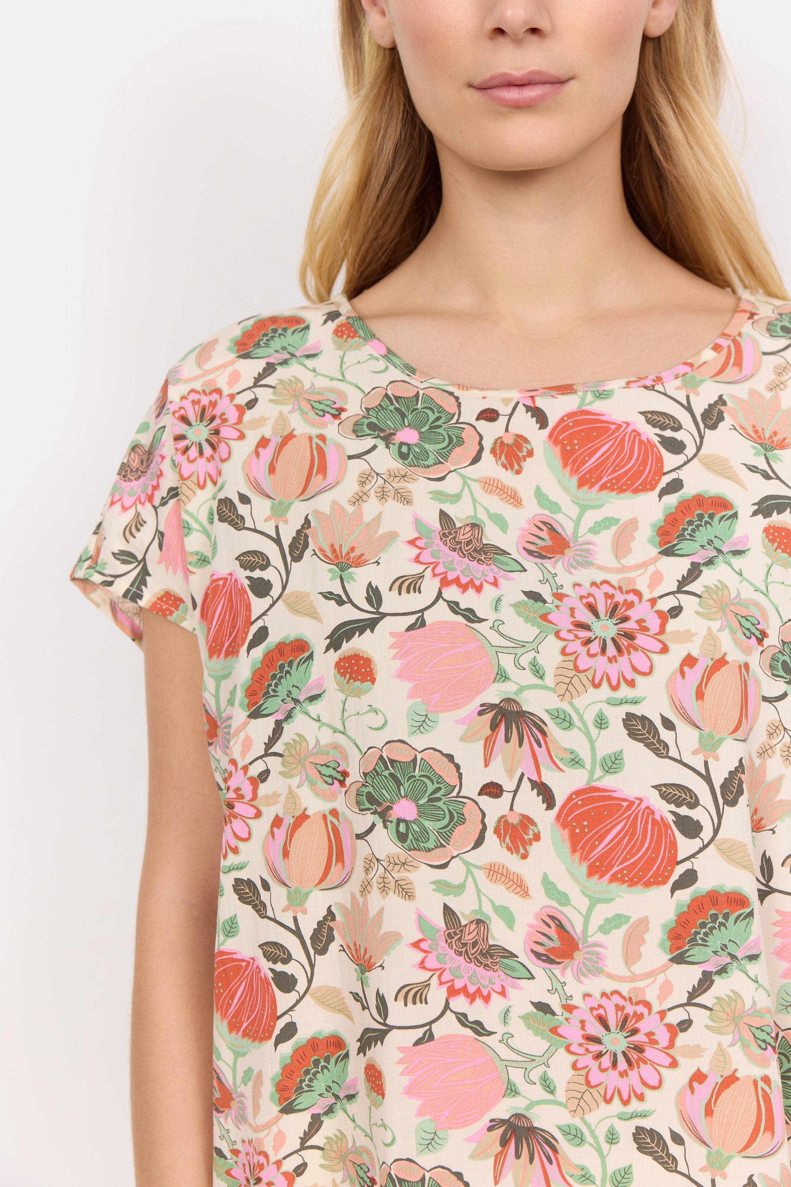Front close up of Soya Concept (40579) Women's Short Sleeve Graphic Floral Blouse in a Peach Floral Print With PInk & Green Hues over a Cream Background 