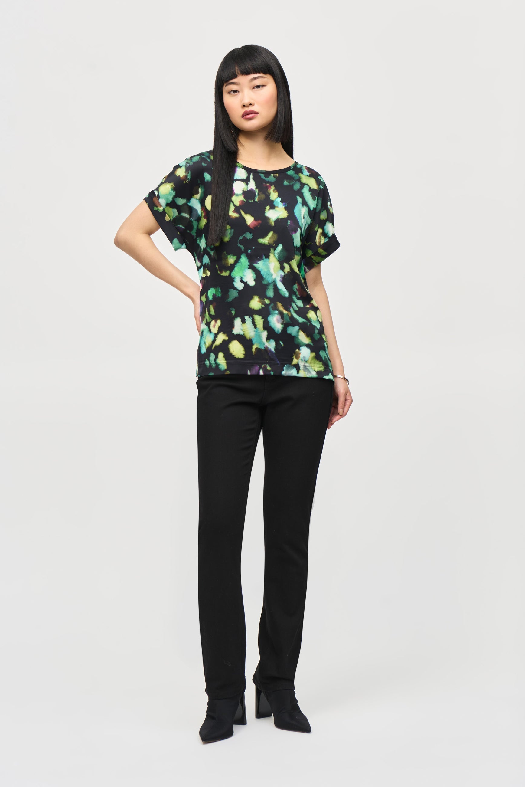 Front view of Joseph Ribkoff (243938) Women's Short Dolman Sleeve Top With Green Abstract Printed Satin Front and Black Silky Knit Back