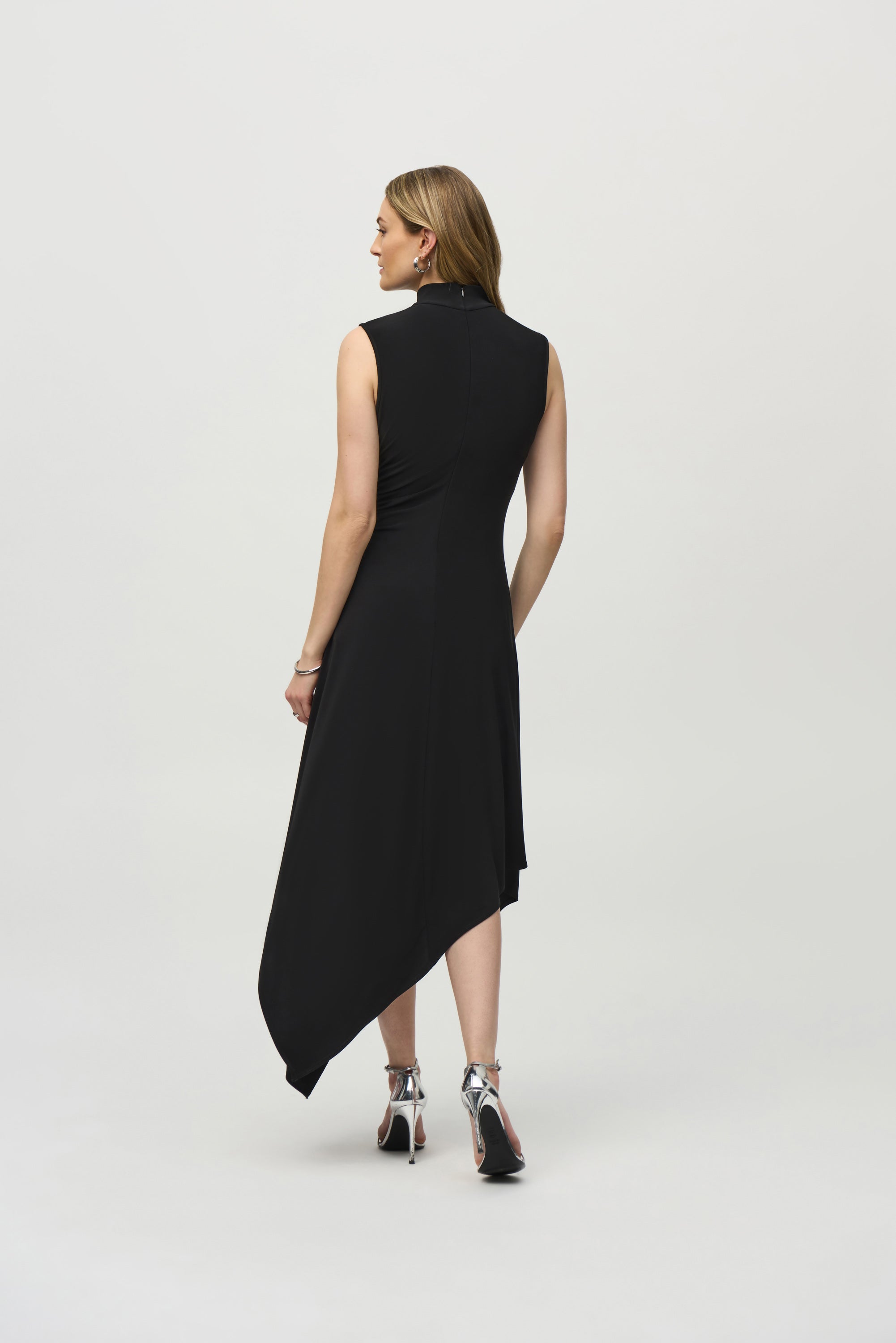 Back View of Joseph Ribkoff (244038) Sleeveless Silky Knit Fit and Flare Dress with Turtleneck and Asymmetrical hemline in Black