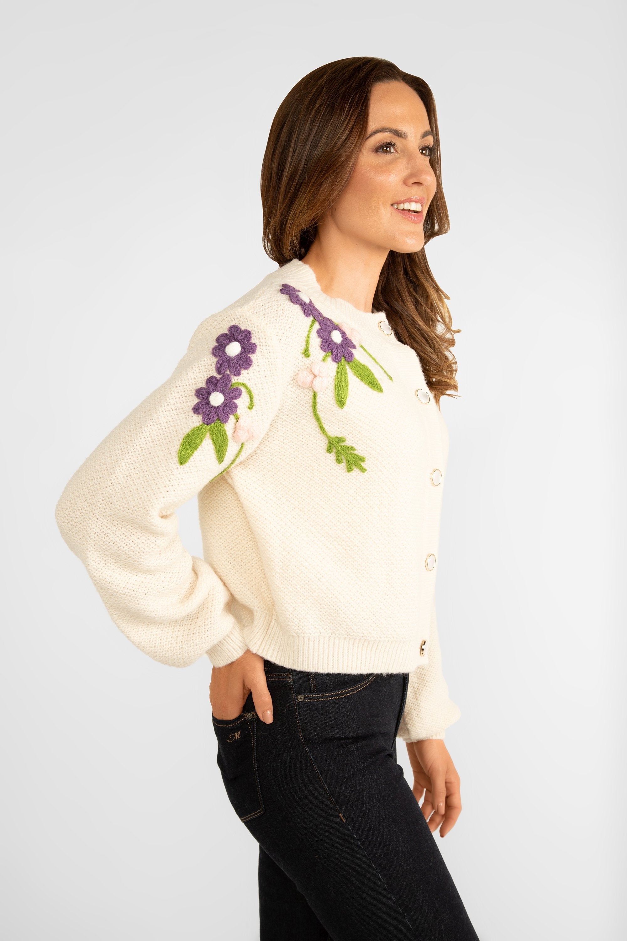 Side view of Astrid (17-WT045F) Women's Woodstock Cardigan - Cream medium weight knit with long sleeve and crew neck with pink and purple floral embroidery along shoulders