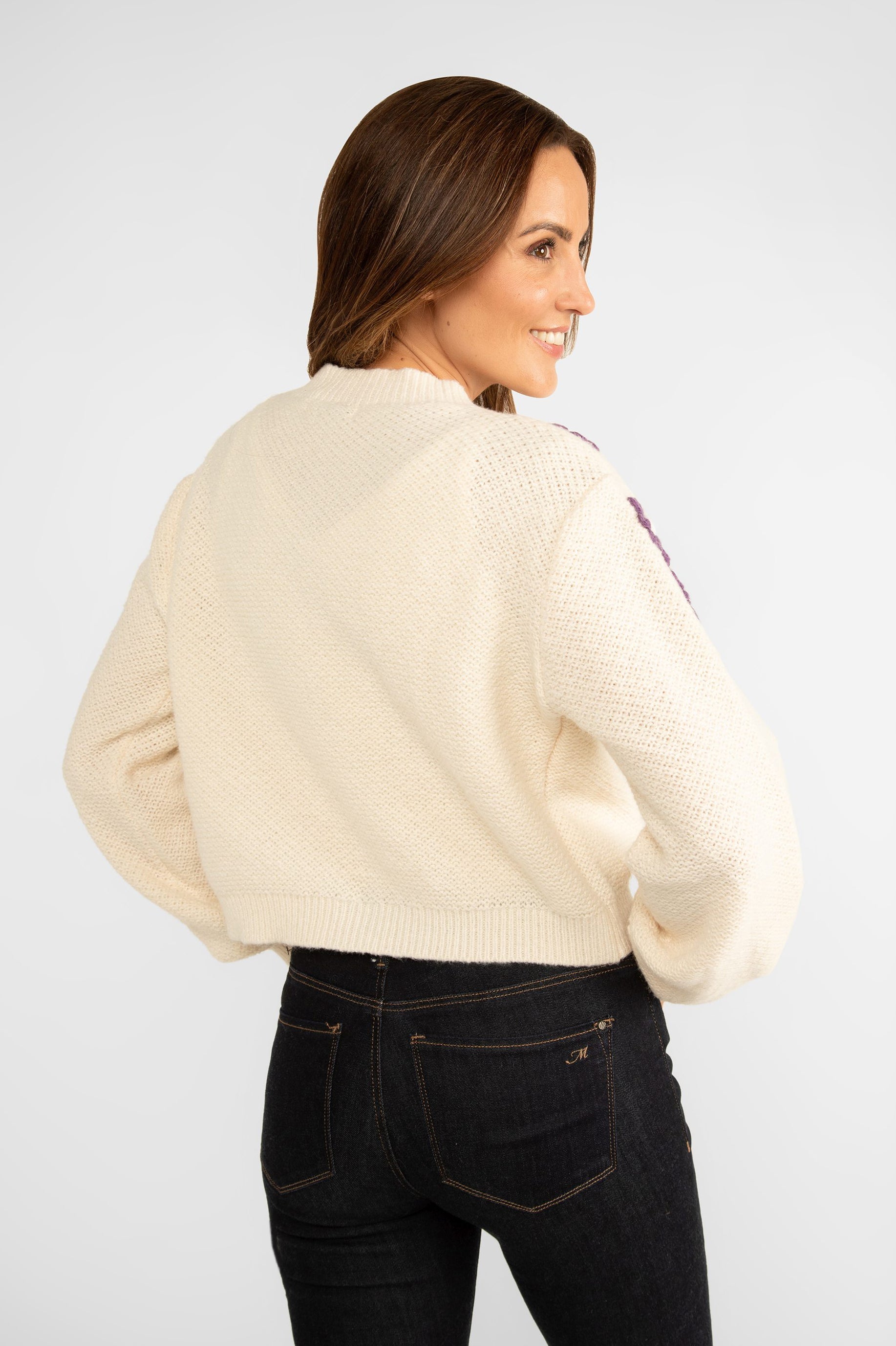 Back view of Astrid (17-WT045F) Women's Woodstock Cardigan - Cream medium weight knit with long sleeve and crew neck with pink and purple floral embroidery along shoulders