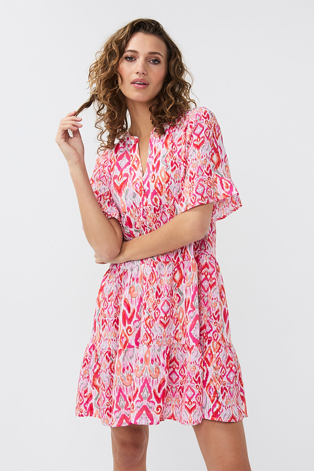 Front view of EsQualo (HS2415214) Short Sleeve Pink Ikat Printed Seersucker Dress with tiered mini skirt, split v-neck and a relaxed fit 