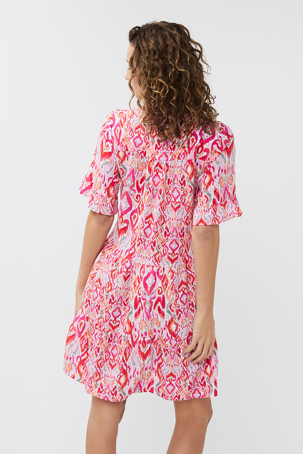 Back view of EsQualo (HS2415214) Short Sleeve Pink Ikat Printed Seersucker Dress with tiered mini skirt, split v-neck and a relaxed fit 