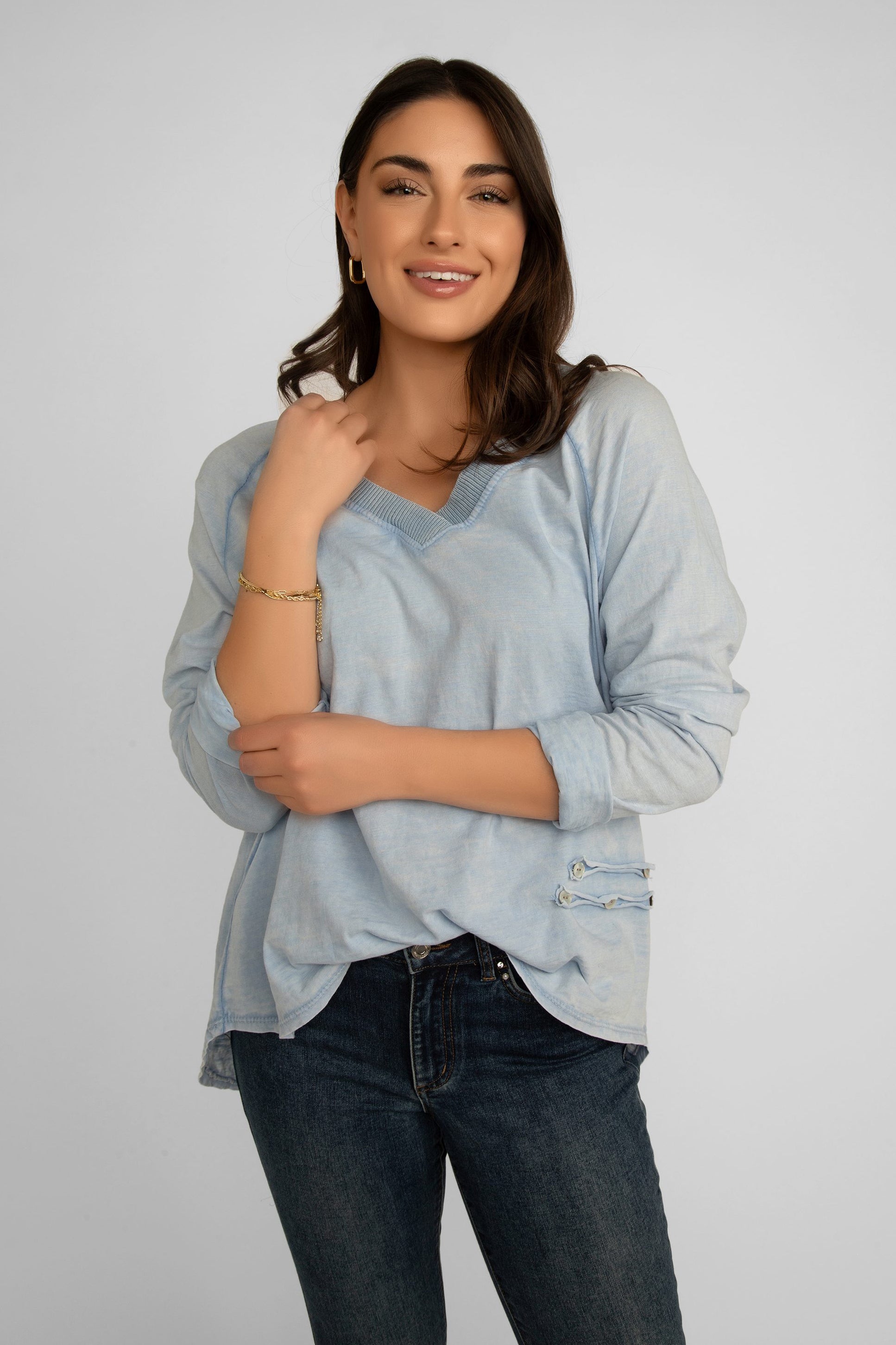 Front view of Elissia (JY3734) Women's Long Raglan Sleeve Garment Dye V-Neck Top with Button Patch Detail on left hip, and a high low hem in Baby Blue