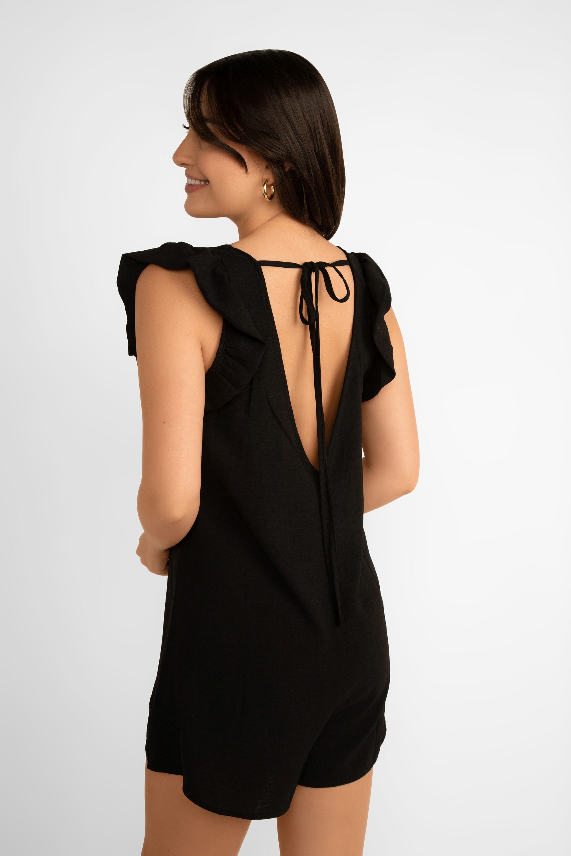 Back view of Pink Martini (RO-110232) Women's Sleeveless Romper with ruffles on shoulders, v-neck, and plunging back in black