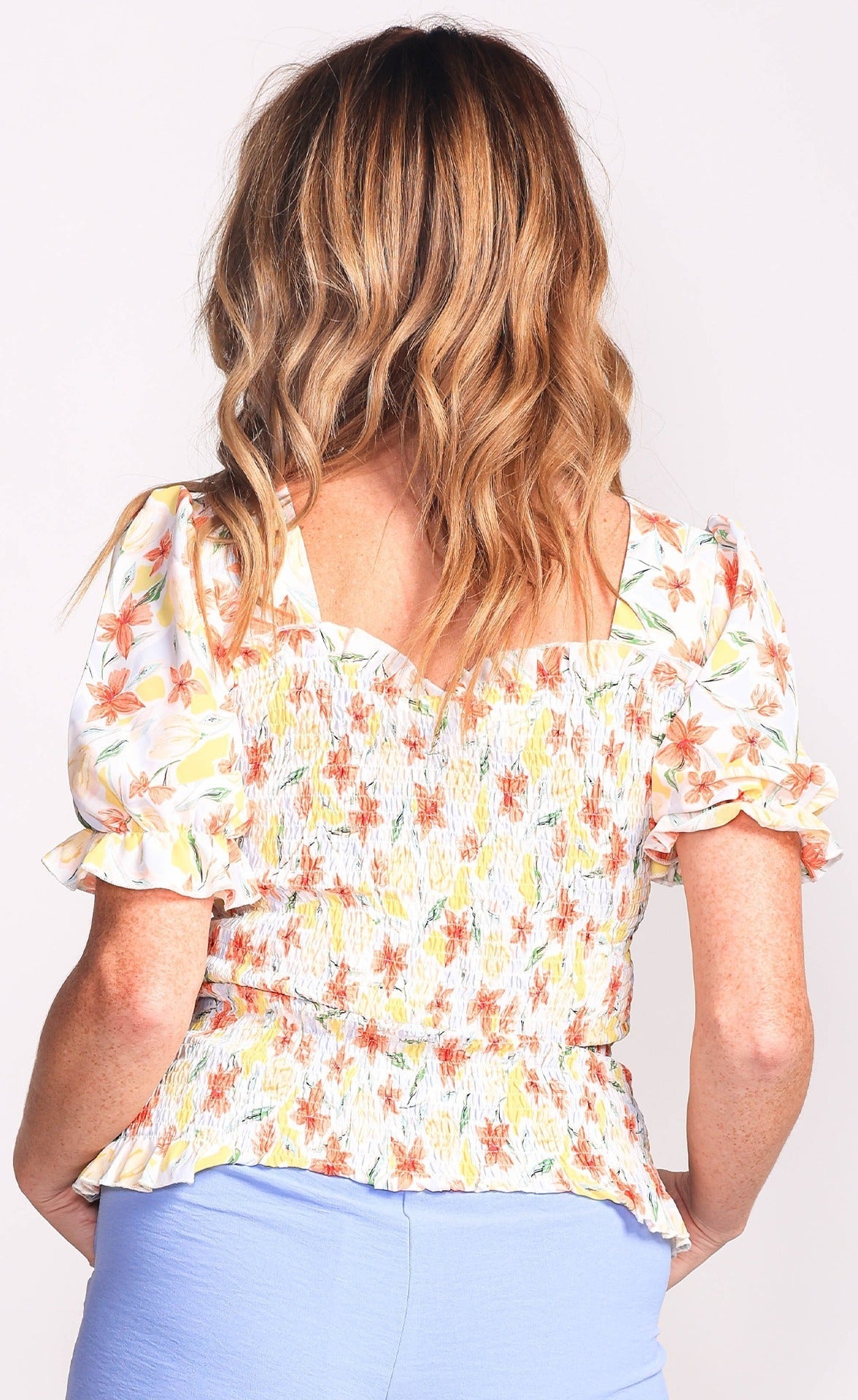 Back view of Pink Martini (TO-230504) Zinnia Top - Women's Short Puff Sleeve Top with Square Neck and Smocked Bodice in a yellow and orange floral print